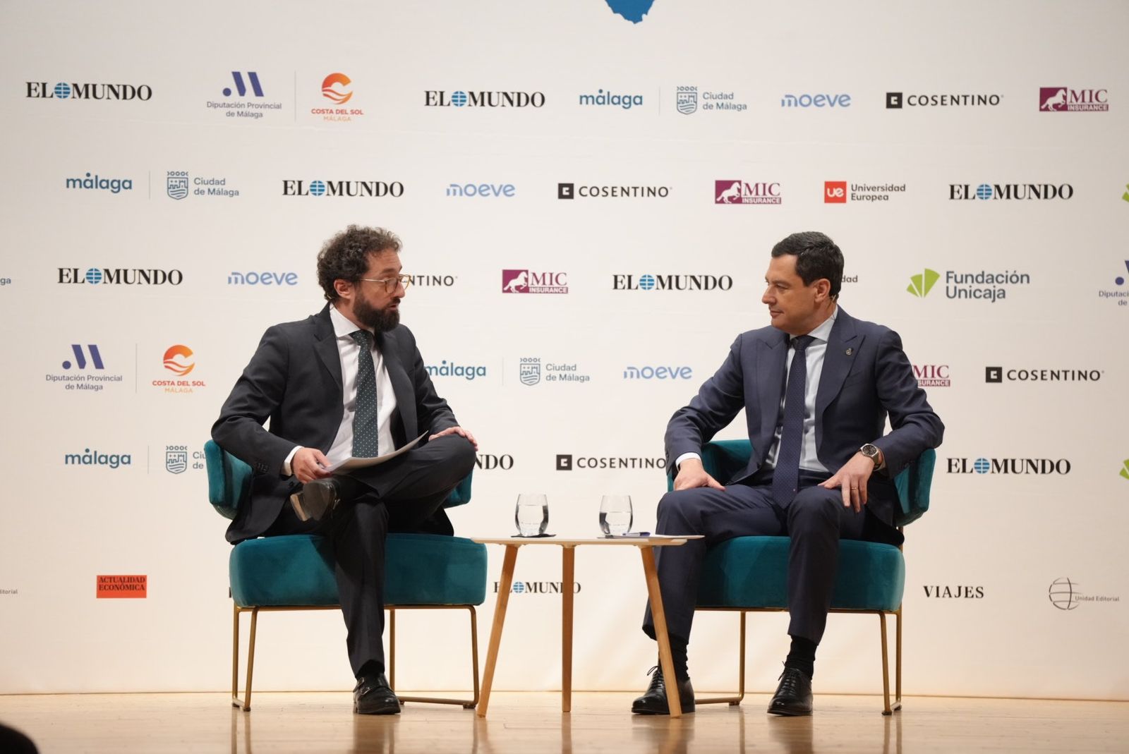 El presidente de la Junta de Andalucía, Juanma Moreno, conversa con el director de El Mundo, Joaquín Manso, en un foro informativo en Málaga.